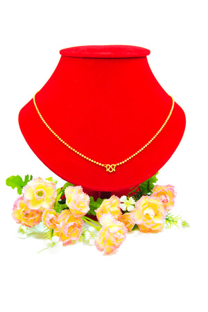 Gold necklace putting on red cloth with flowers isolated on white backgroundの写真素材