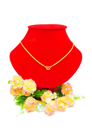 Gold necklace putting on red cloth with flowers isolated on white backgroundの写真素材