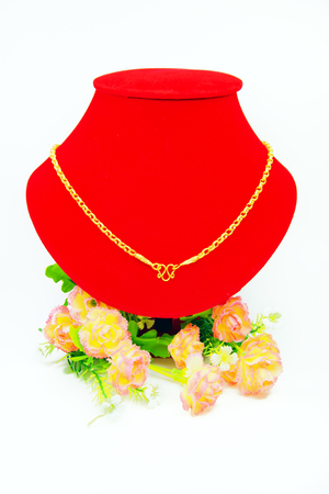 Gold necklace putting on red cloth with flowers isolated on white backgroundの写真素材