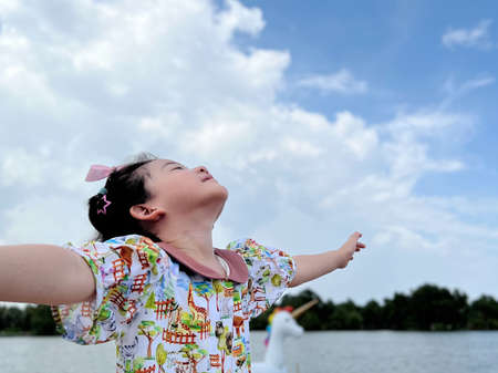 cute little girl looks into the bright day sky for new opportunitiesの写真素材