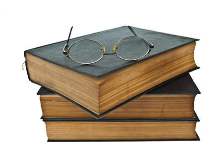 Stack of old books with eye glasses isolated on white backgroundの写真素材