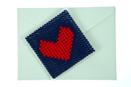 Green envelop with red knitted heart isolated on white background