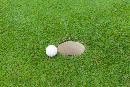 Golf ball on lip on cupの写真素材