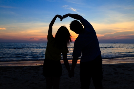 Asian boy and girl with heart shape on the sunset beachの写真素材