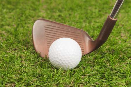 Golf ball on green grass with iron club closeupの写真素材