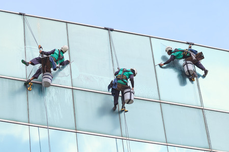 group of workers cleaning windows service on high rise buildingの写真素材