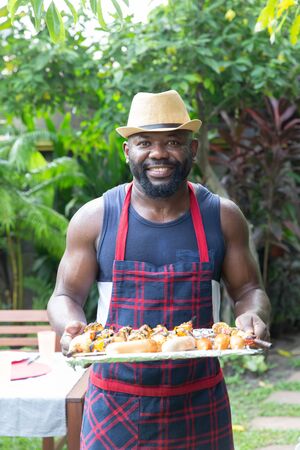 Man cooking meat on barbecue grill for house backyard partyの写真素材