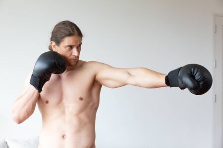 An asian man has boxing training in his living room at homeの写真素材