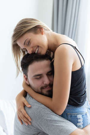 Passionate couple is hug and kiss on bed in their white bedroomの写真素材
