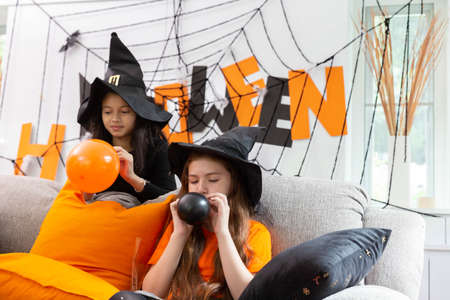 Happy Halloween by a group of children, a sister in carnival costume prepare the colorful balloon in decorated houseの写真素材