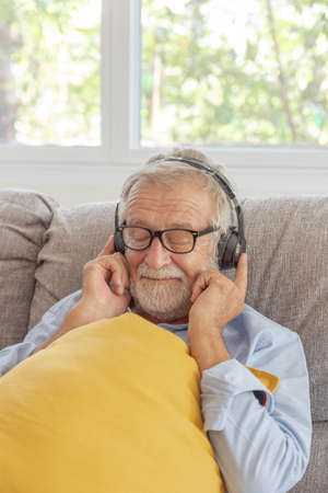 Senior retirement man listen to music using headphone feeling happy in his home