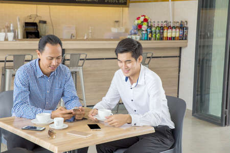 Two Asian businessmen discussing while having coffee together