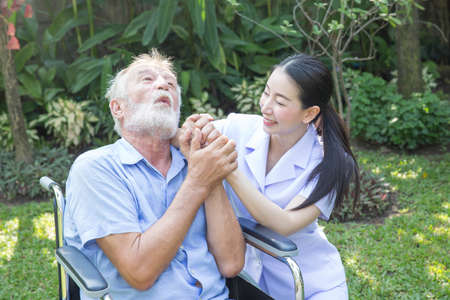 A nurse take care a senior male on wheelchair in his garden at homeの写真素材