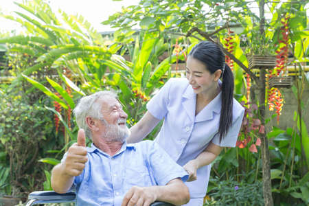 A nurse take care a senior male on wheelchair in his garden at home
