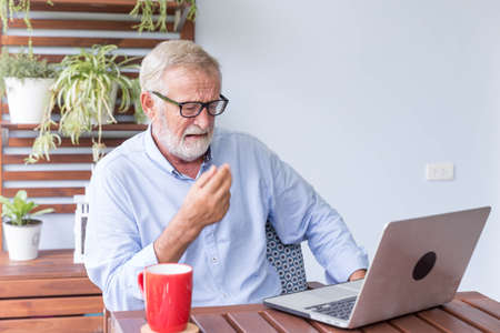 Senior retirement man is working with his laptop at home feeling unhappy
