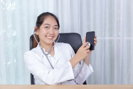 Female doctor use stethoscope to check mobile phone as a mobile phone health check serviceの写真素材