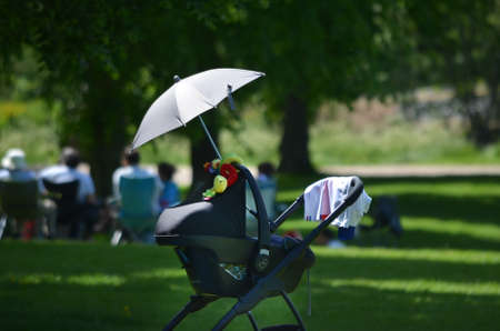 This picture features a stroller with a umbrella on it with people in the backgorund.の写真素材