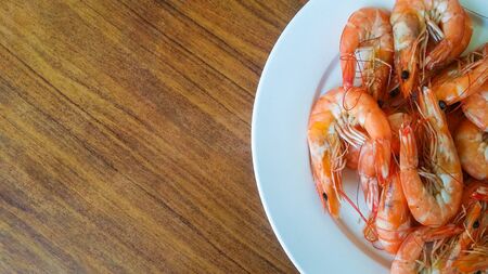 Baked shrimp in a white plate on wooden tableの写真素材