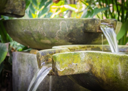 Flowing water from stone basin in the gardenの写真素材