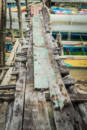 An old grunge wooden bridge at the pier when low tideの写真素材