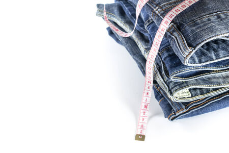 heap of jeans trousers with tape measure isolated on white