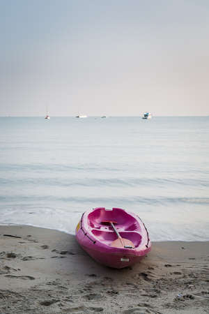 Pink kayak boat on the beach with paddleの写真素材
