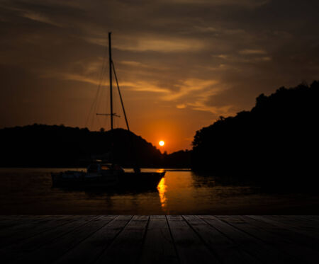 Scenery of wooden pier with sailboat and dramatic sky sunset, Phuket, Thailandの写真素材