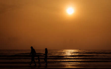 Silhouette people walking on the beach with warm tone
