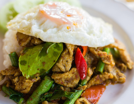 Stir fried pork with curry paste serve with fried egg and steam rice on a dishの写真素材