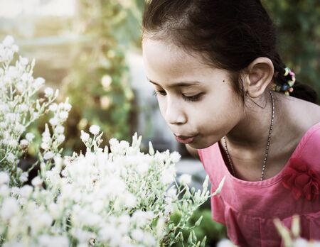 Little cute girl blowing flower in the garden under sunlightの写真素材