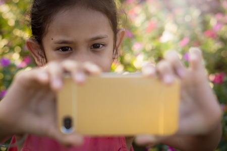 Little girl photographs herself with a meadow of wildflowers under sunlight. Selfieの写真素材