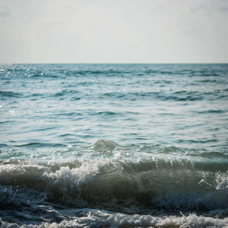 Sea with surf on the beach under sunlight