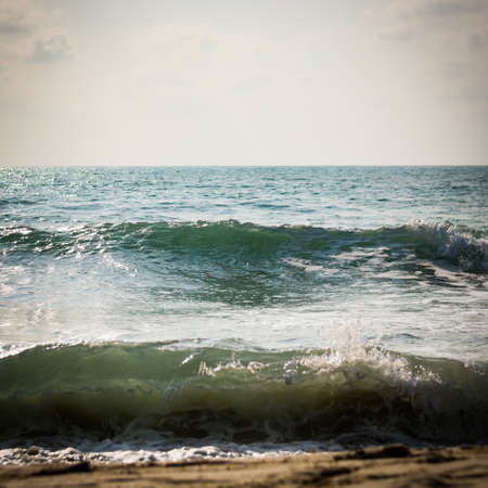 Sea with surf on the beach under sunlightの写真素材