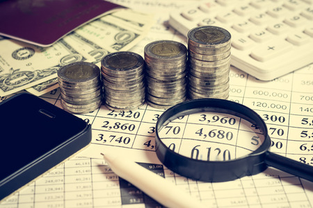 Financial accounting with pen, money, passport, mobile phone, magnifying glass and calculatorの写真素材