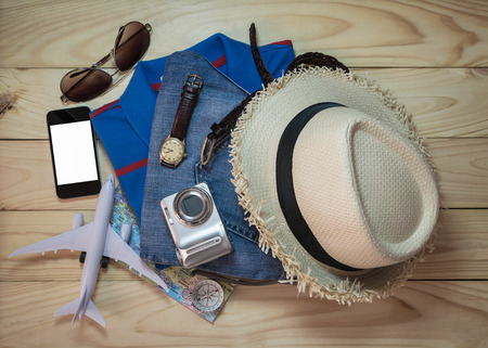 Stack of clothes and travel accessory on wooden plank. Travel concept.の写真素材