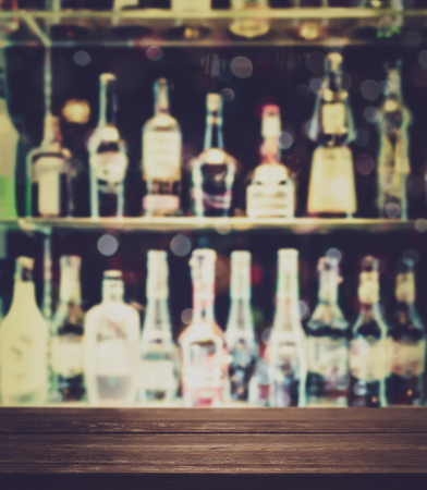 Empty wooden table with blurred alcoholic drinks are on the shelf background. For product display.の写真素材
