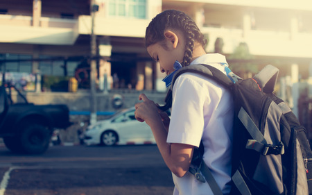 Little schoolgirl walking to school under sunlight. Education concept.の写真素材