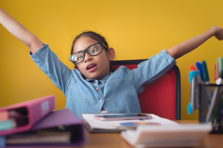 Cute girl raises hands up while smiling with happiness isolated on yellow background. Business girl...