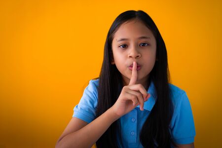 Indoor portrait of pretty asian girl with calm face expression. Photo of serious young girl with black long hair isolated on orange background.の写真素材