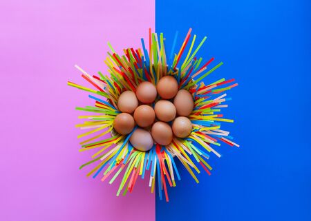 Chicken eggs in a basket on pink and blue paper background, Easter eggs concept.の写真素材