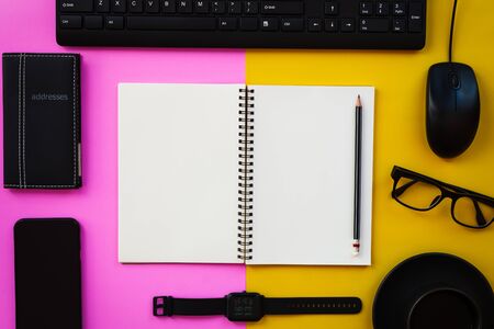 Blank white notepad with black office and personal accessories isolated on two tone pink and yellow background, Business motivation and inspiration concepts.の写真素材