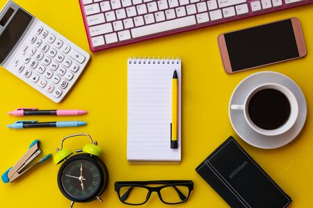 Blank white notepad with office and personal accessories isolated on yellow background, Business motivation and inspiration concepts.の写真素材
