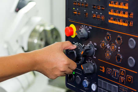 operator use hand turns dial switch control at panel for adjust parameter of cnc lathe machine at factoryの写真素材