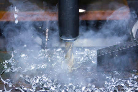 close up tool of automatic drilling machine make hole at metal with cooling by coolant water and...