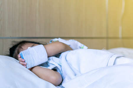 Child or girl patient rest or sleep on bed and hand still lock with equipment medical for injection for saline or vitamin or infusion intravenousの写真素材