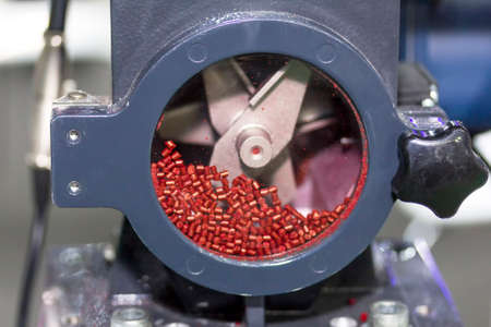 close up red plastic granules in crusher machine with blade of cutting prepare material for...