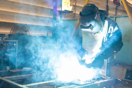 man or worker welding metal part at factory with very smoke and sparkle bright right