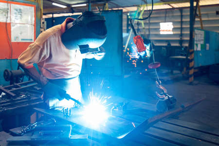 man or worker welding metal part at factory with very smoke and sparkle bright right