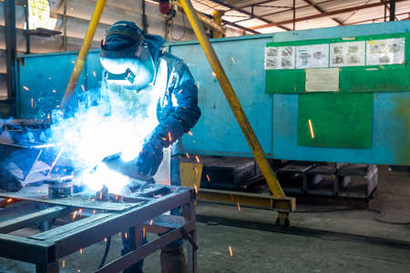 man or worker welding metal part at factory with very smoke and sparkle bright right
