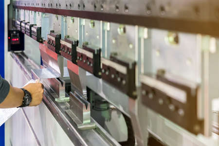 Close up teeth of semi automatic bending machine and hand of man hold metal sheet during working